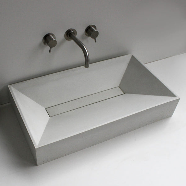 Vara concrete sink installed in a modern bathroom with wall-mounted faucets, blending artisanal craftsmanship with contemporary design – Unrefined Design.